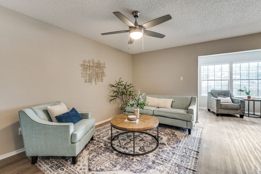 a living room with couches and a coffee table and a ceiling fan